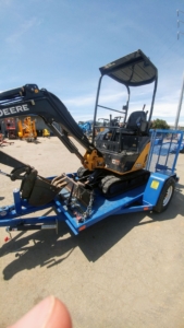 excavator on a blue trailer to be rented