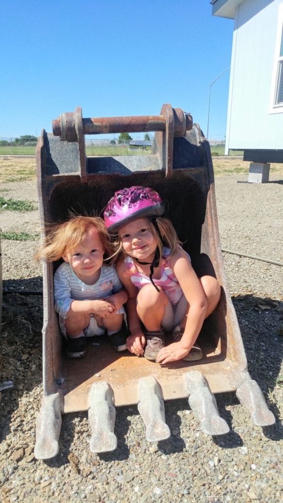 Two little girls in a backhoe bucket