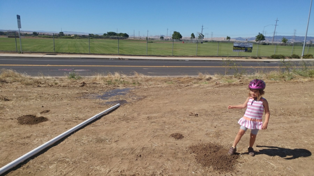 little girl by a pipe pushing water