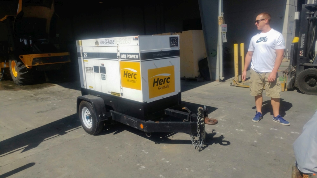 man standing by a 20kw generator by herc rentals