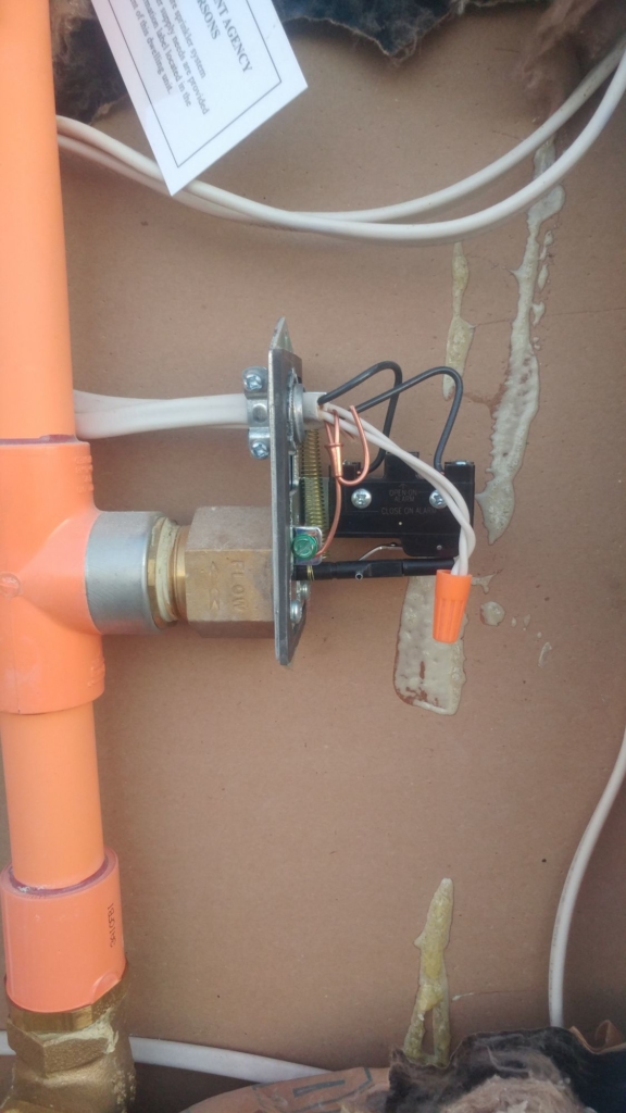 Sprinkler bell controller next to an orange pipe