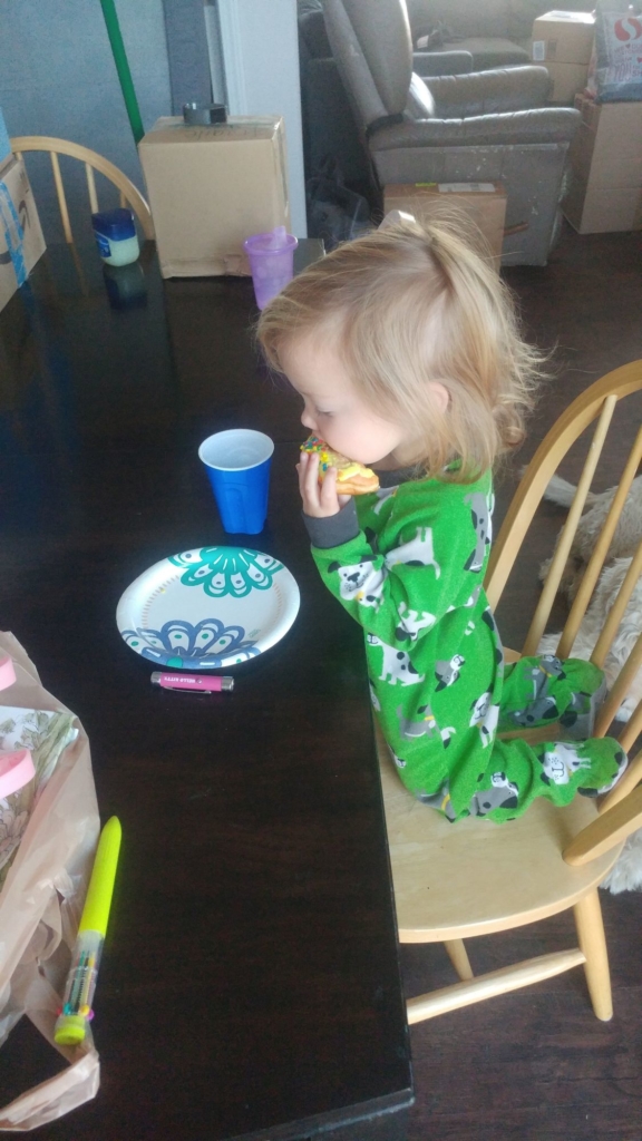 a little girl in green pajamas eating a donut