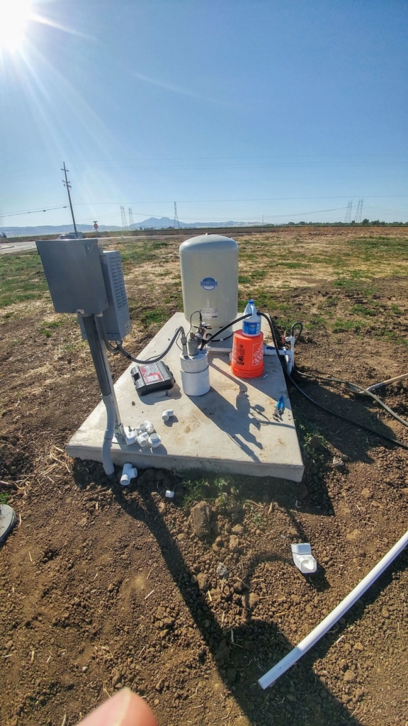 A rural well with a bottle of bleach on a bucket