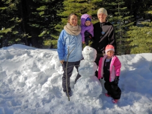 family taking a picture with a snowman