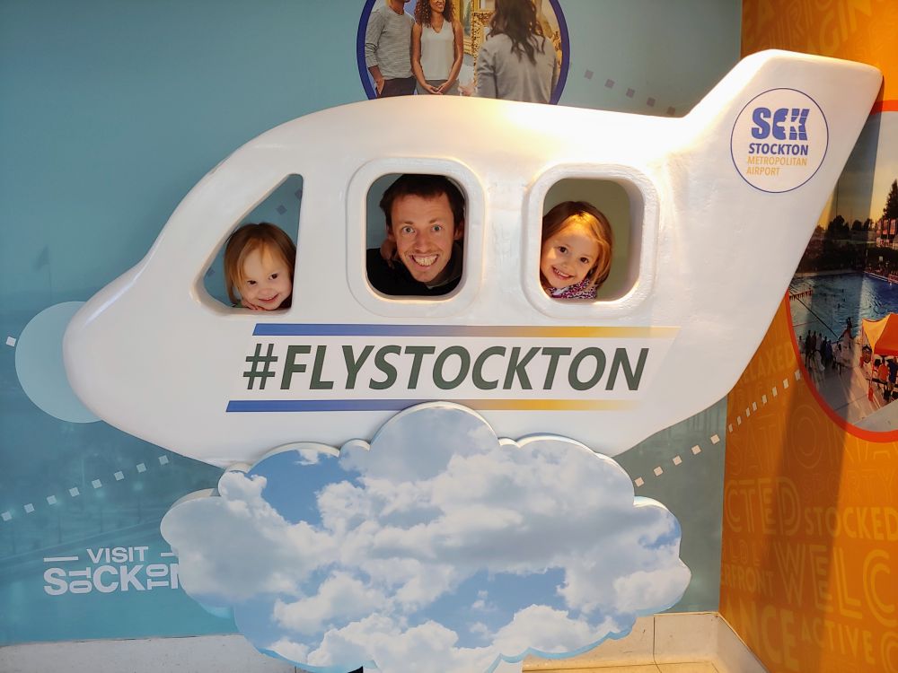 man and two little girls in a airplane frame smiling